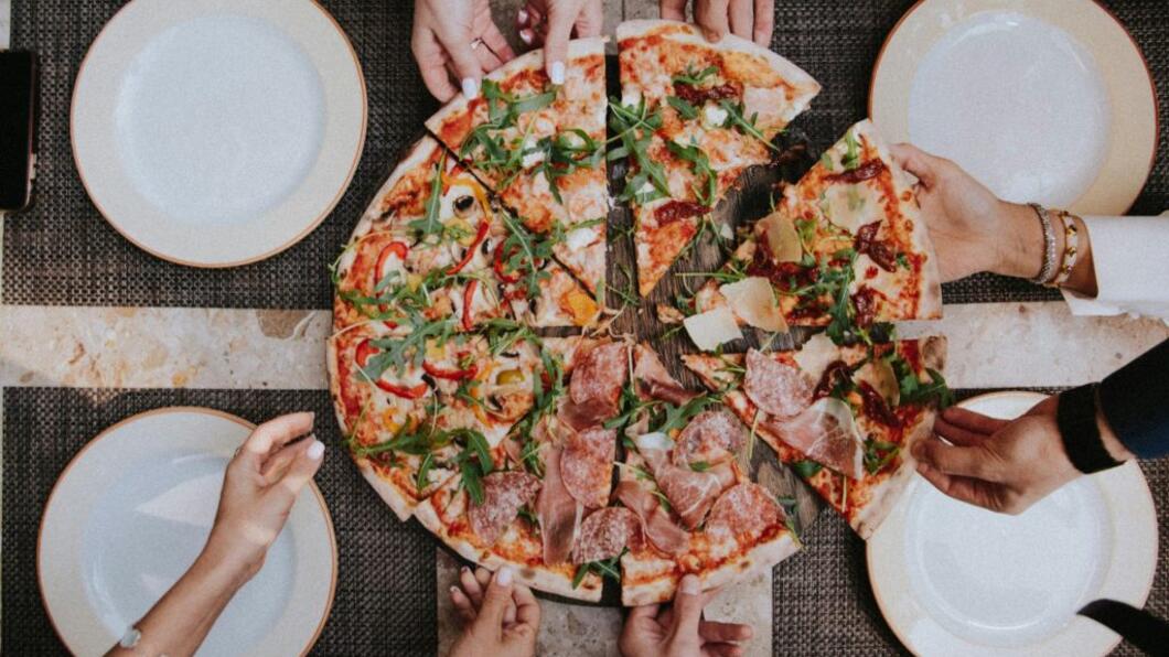 foto van grote pizza met handen die punten pakken